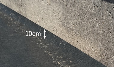 防草シートを壁際に10cm程度立ち上げて施工している様子