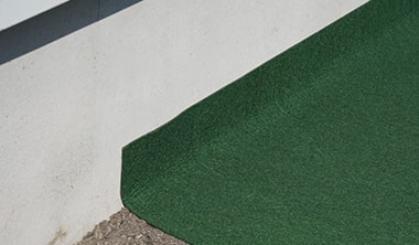 柔軟性の高い防草シートが、壁際にぴったり沿っている様子